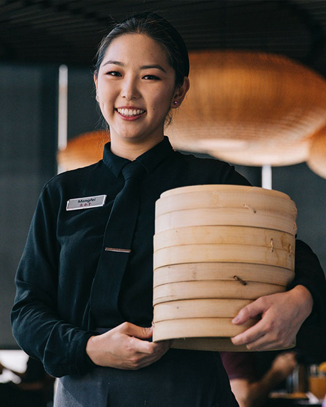 微笑的服務生拿著一籃小籠包。