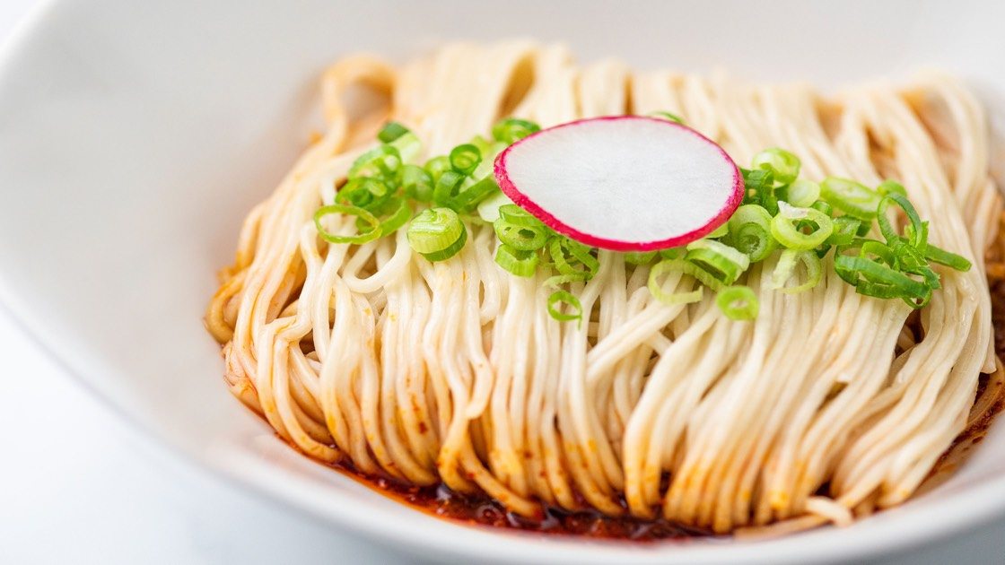 Noodles with Spicy Sauce in a white bowl, close up