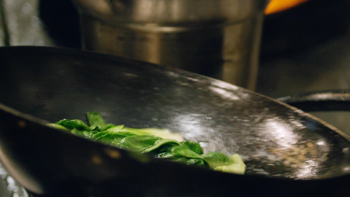 Bok choy being cooked in a pan.