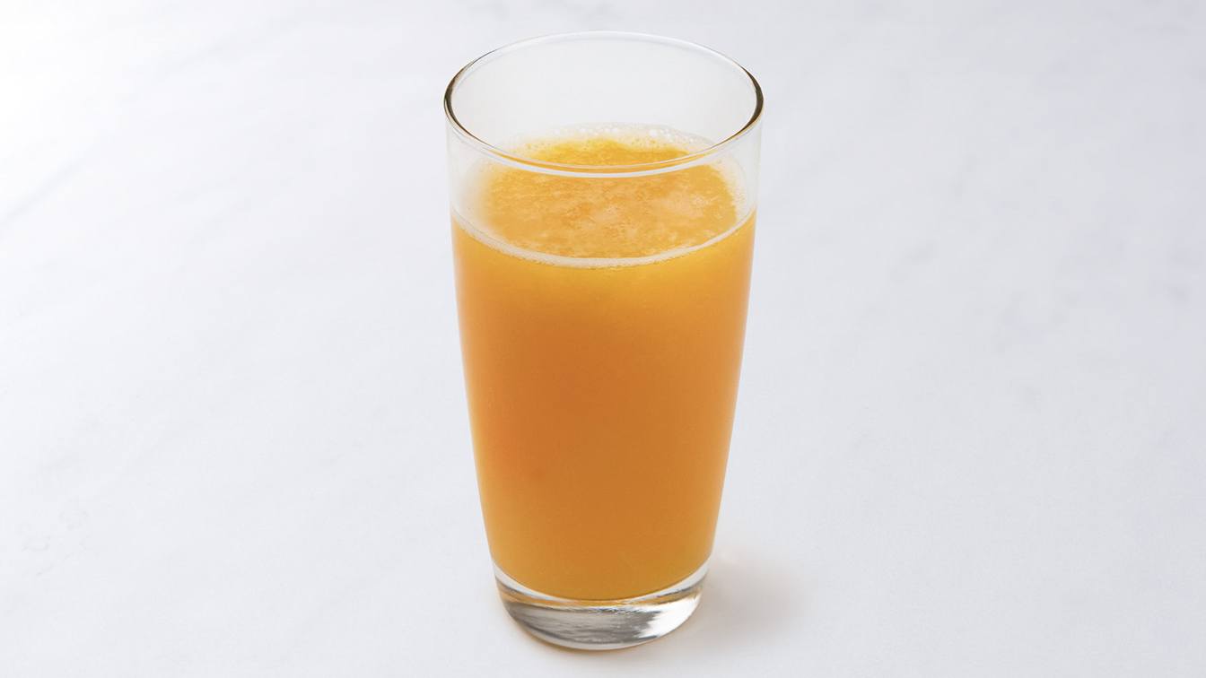 Glass of fresh squeezed OJ on white background