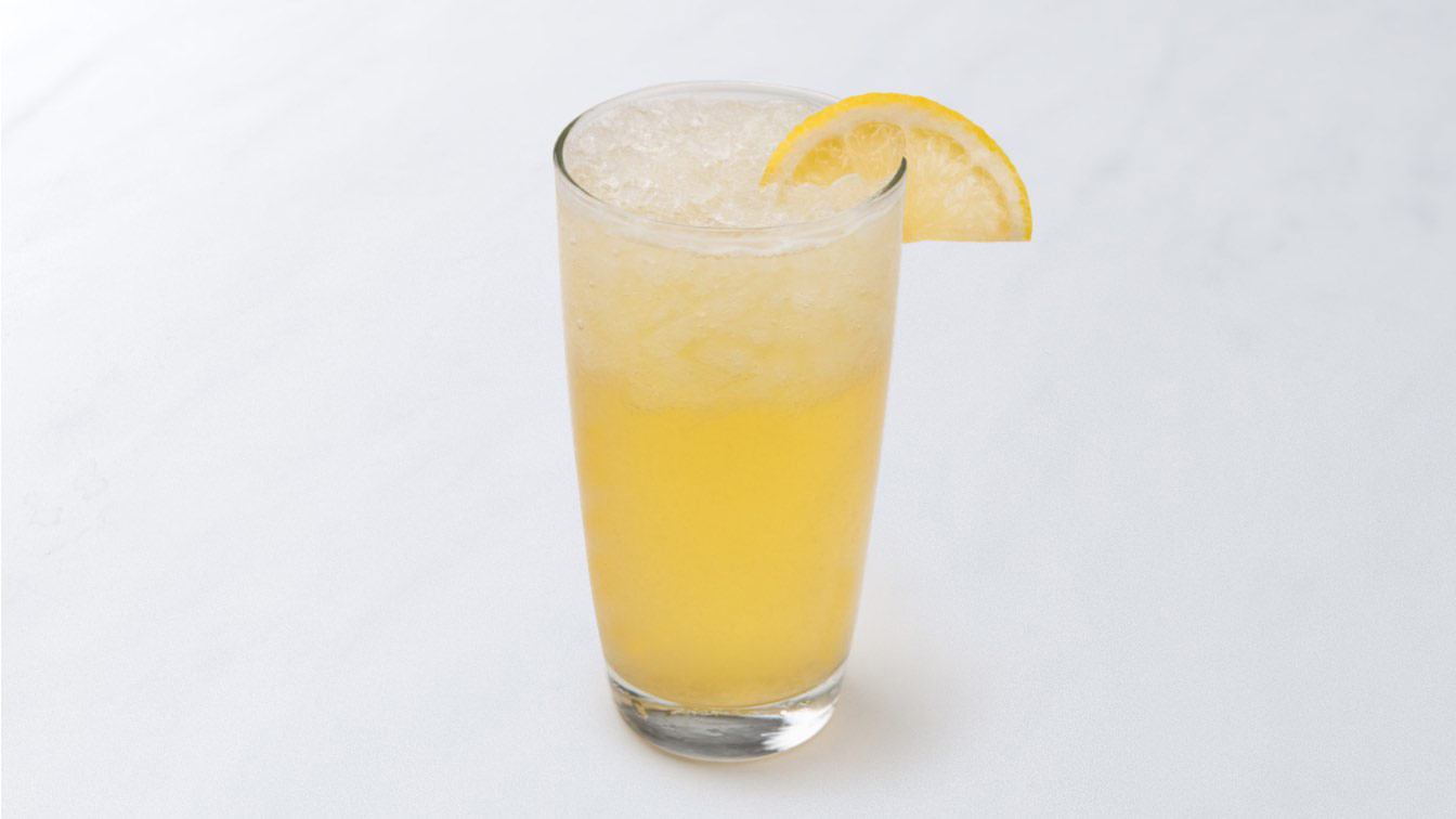 A photo of ice honey lemonade with a lemon slice garnish in a glass.