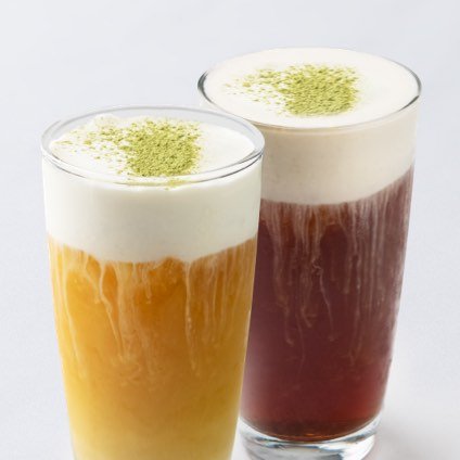 A photo of two sea salt cream-topped black and green teas in side-by-side glasses.
