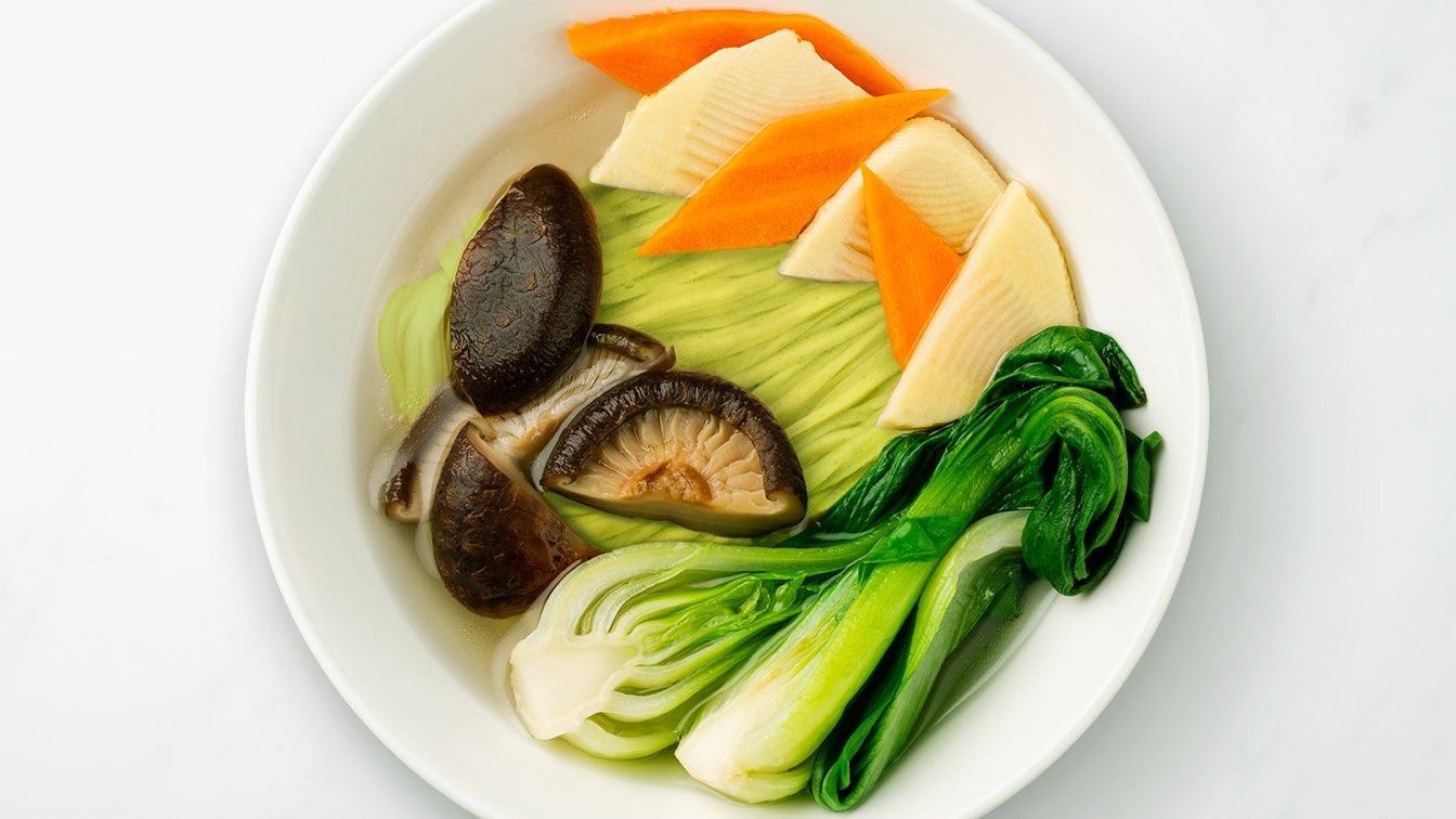 White bowl filled with vegan noodles, mushrooms, and bok choy