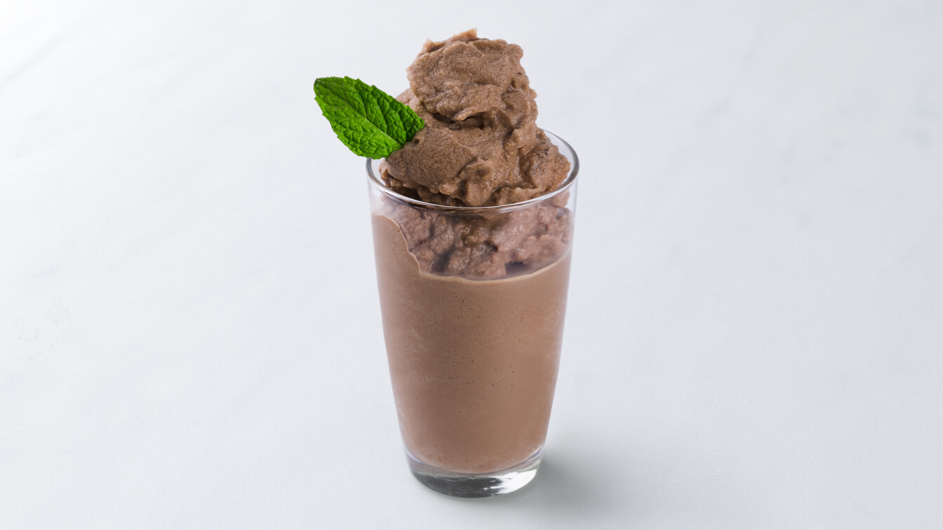 A mocha smoothie in a glass topped with mint garnish